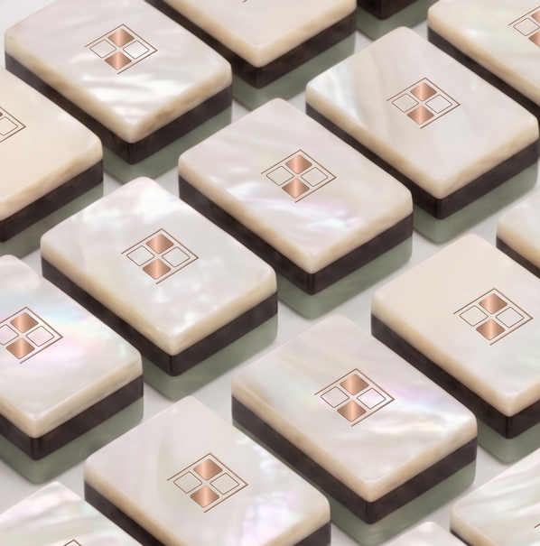 Mother-of-pearl Mise en Mahjong tiles arranged in rows showing the rose-gold four-square mark