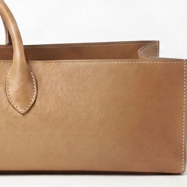 Tan saddle leather handbag detail showing top-stitching and strap