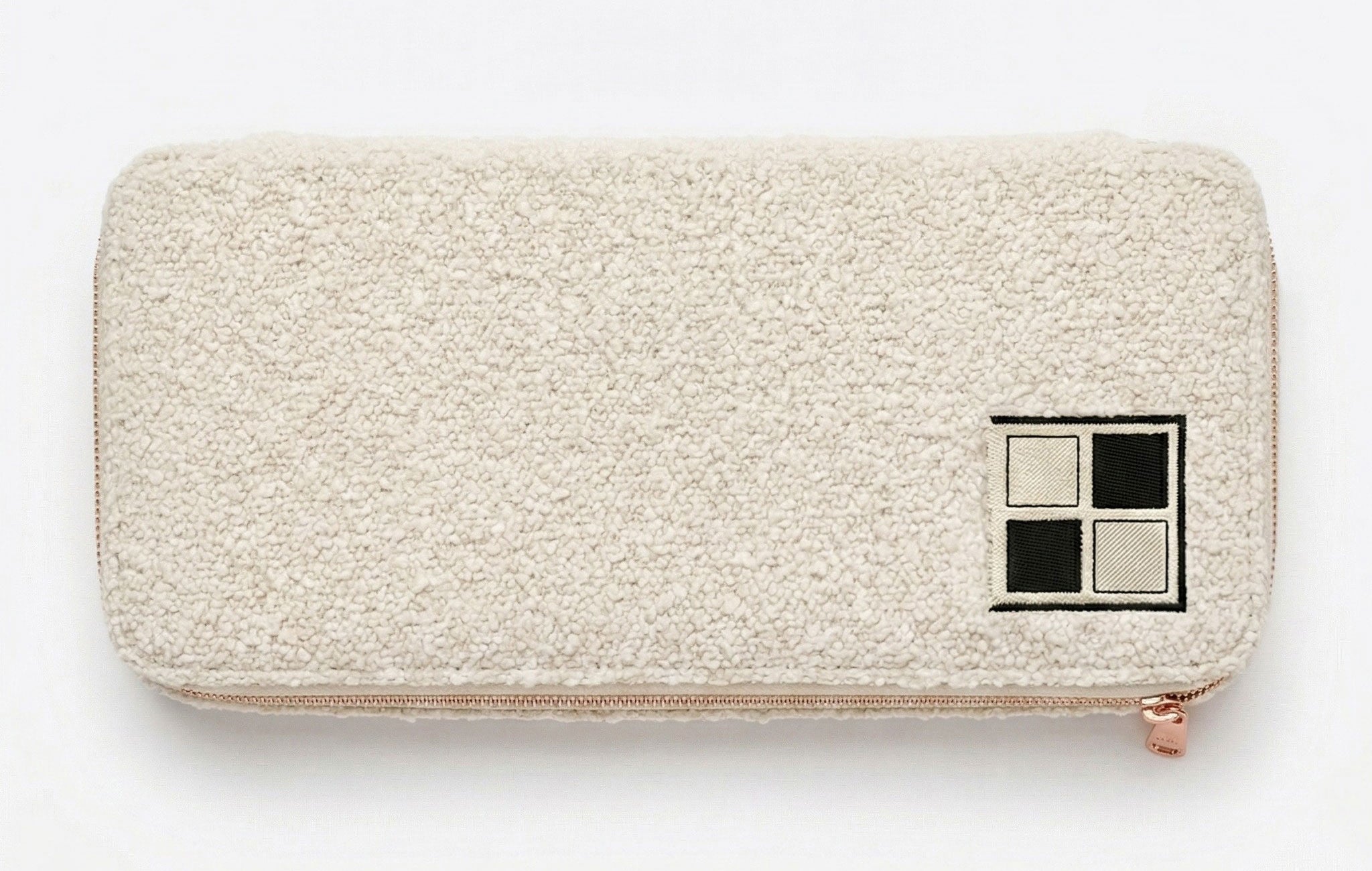 Ivory bouclé tile storage bag with rose-gold drawstring.